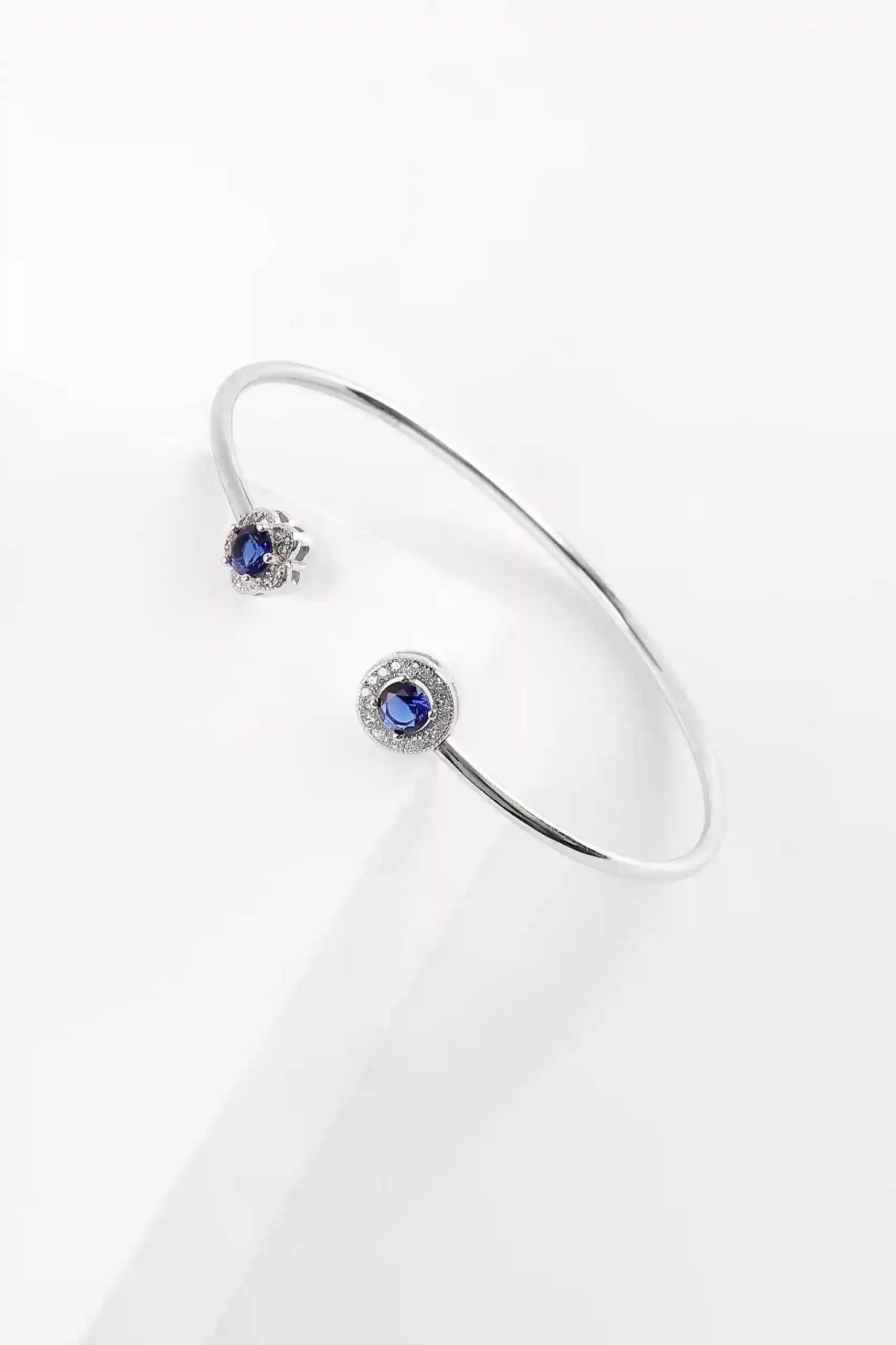 Viorette Bloom open bangle in 925 sterling silver with a blue sapphire-colored floral stone