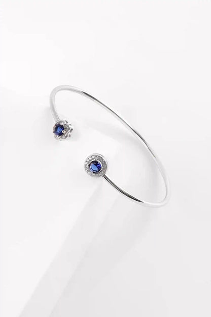 Viorette Bloom open bangle in 925 sterling silver with a blue sapphire-colored floral stone